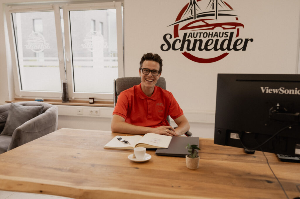 Autohaus Herr Schneider, Mario Schneider als Verkäufer am Schreibtisch